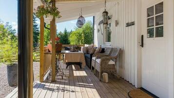 A covered porch with a seating area, a table, and hanging decorations.