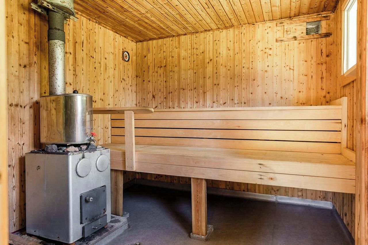 Ein Saunaraum mit einer Holzbank und einer Saunaanlage mit Bedienelementen.