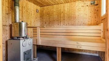 Ein Saunaraum mit einer Holzbank und einer Saunaanlage mit Bedienelementen.