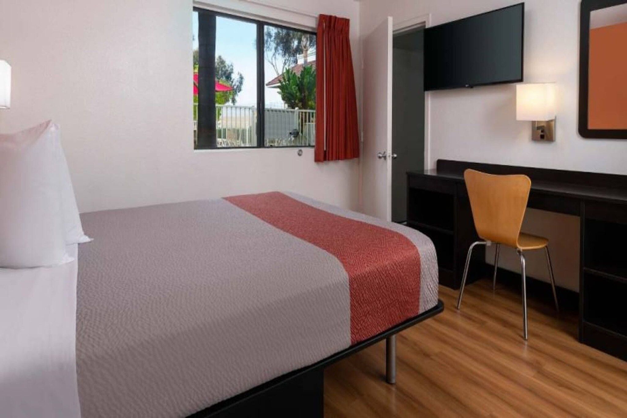 Une chambre d’hôtel avec un lit, un bureau, une chaise et un téléviseur.