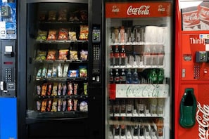 Máquina de vendas com lanches e um refrigerador de Coca-Cola com diversas bebidas.