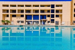 Ein Hotel mit Schwimmbad, mehreren Balkonen und Liegestühlen.