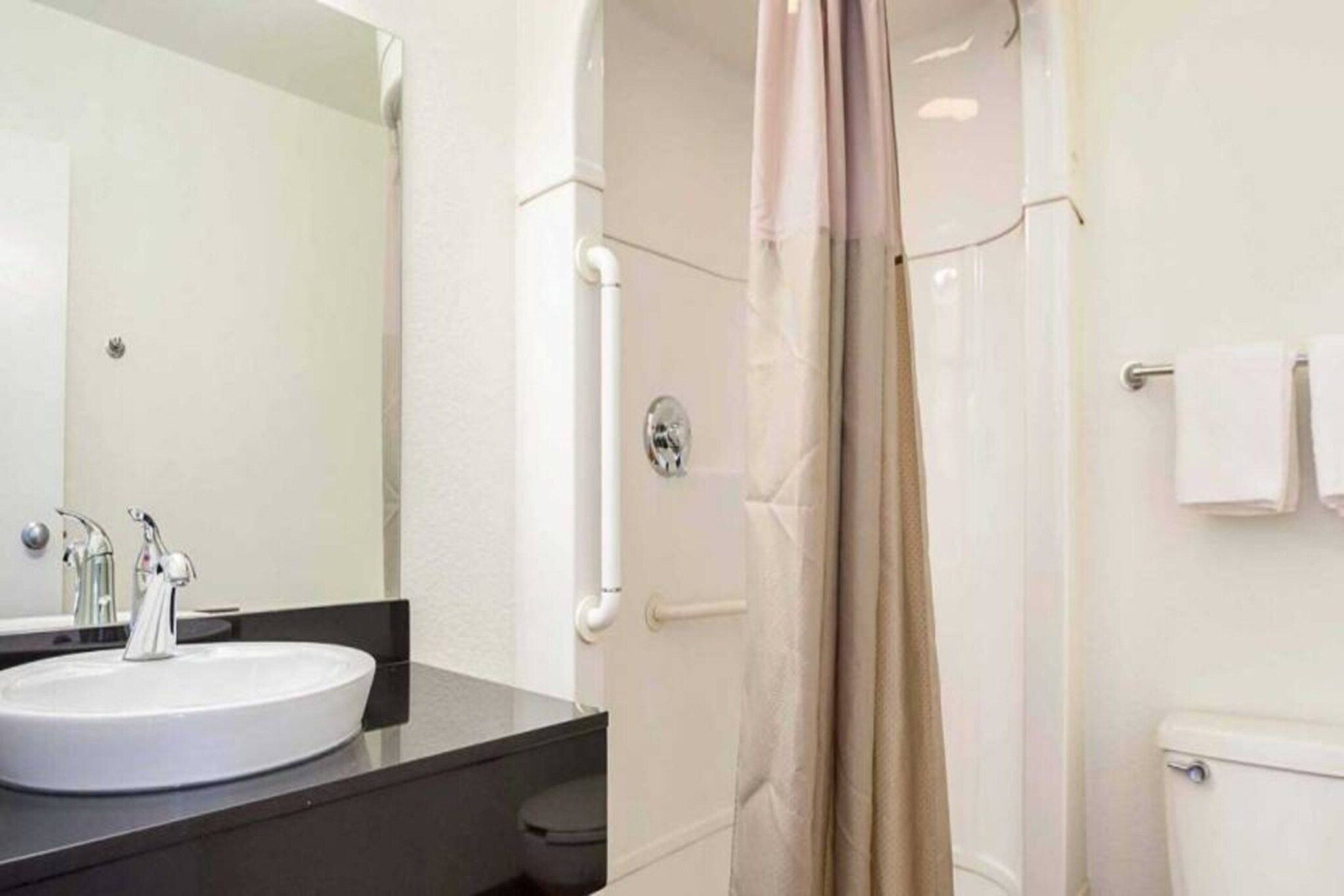 Ein Badezimmer mit Waschbecken, Spiegel, Dusche und Toilette.