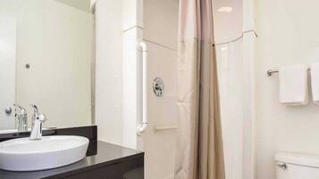 Ein Badezimmer mit Waschbecken, Spiegel, Dusche und Toilette.