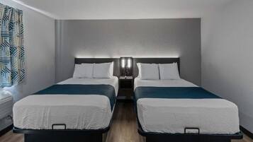 Ein Hotelzimmer mit zwei Betten, einem Nachttisch mit Lampe und einem Fenster mit Vorhängen.