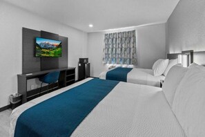 A hotel room with two beds, a desk with a chair, a television, and a patterned window curtain.