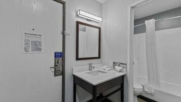 A bathroom with a sink, mirror, and shower curtain.