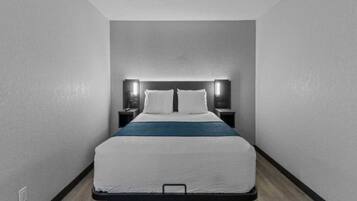A modern hotel room with a single bed, bedside tables, and a headboard with integrated lighting.