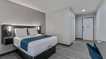 Ett hotellrum med en säng, ett nattduksbord och ett skrivbord med en stol.