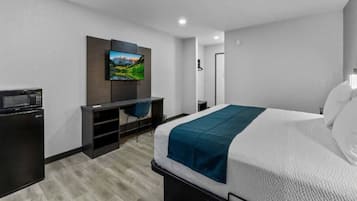 A hotel room with a bed, a desk, a television, and a microwave.