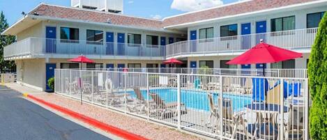 A motel with a swimming pool, multiple balconies, and outdoor seating areas.