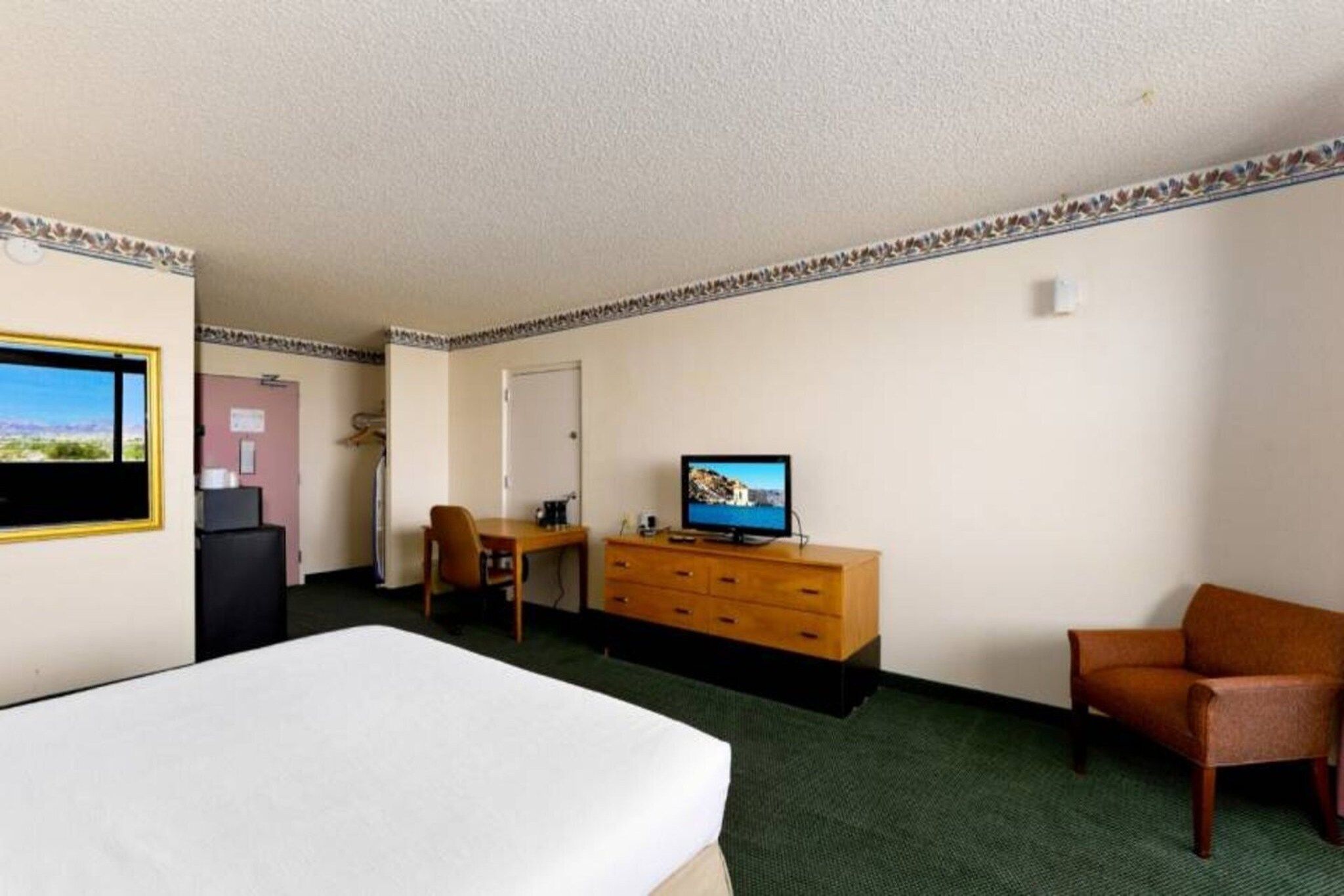 Een hotelkamer met een bed, een bureau, een televisie en een stoel.