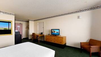 Een hotelkamer met een bed, een bureau, een televisie en een stoel.