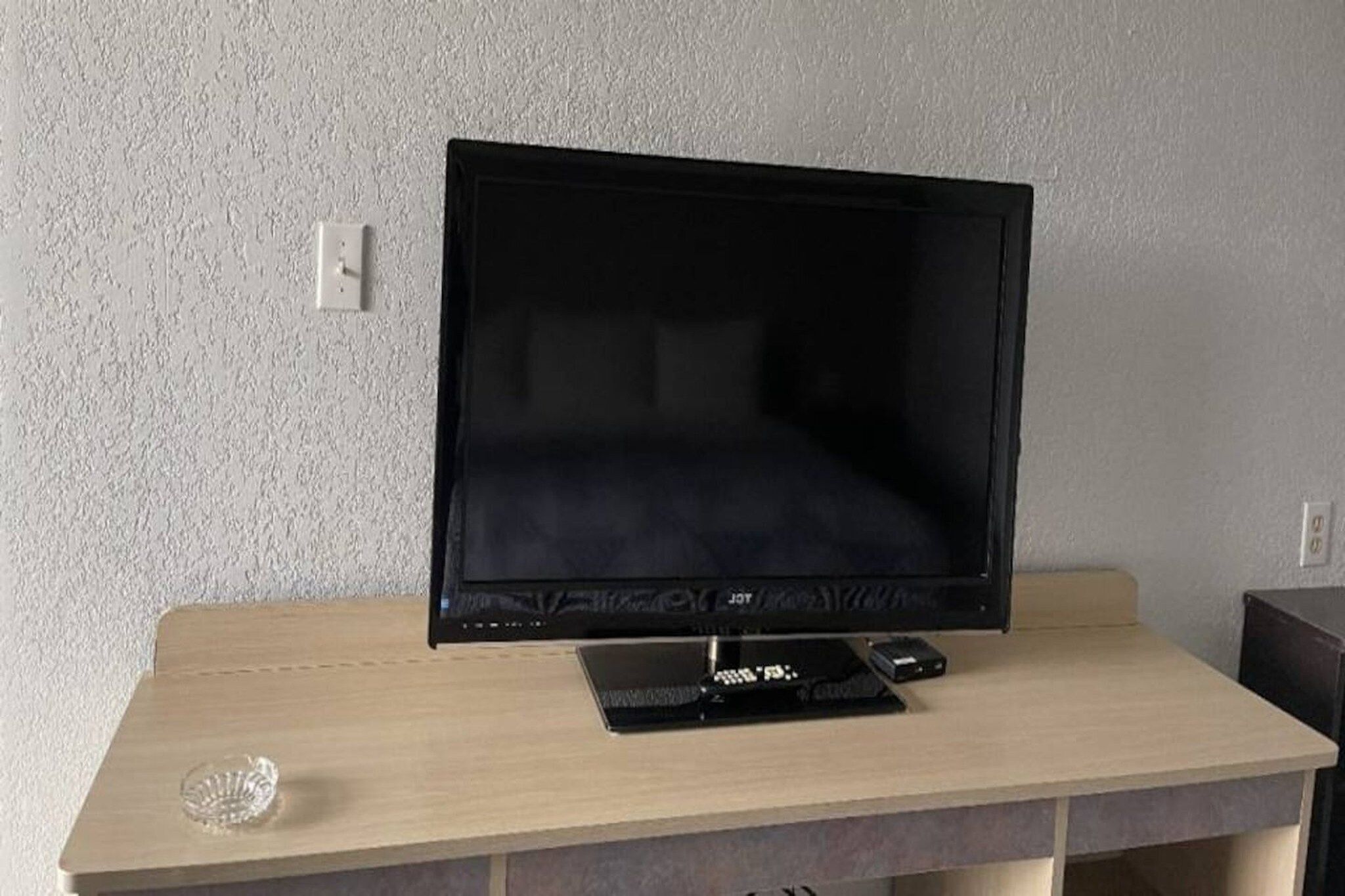 Ein Flachbildfernseher auf einem Holztisch mit Fernbedienung und einer kleinen Dekoration.