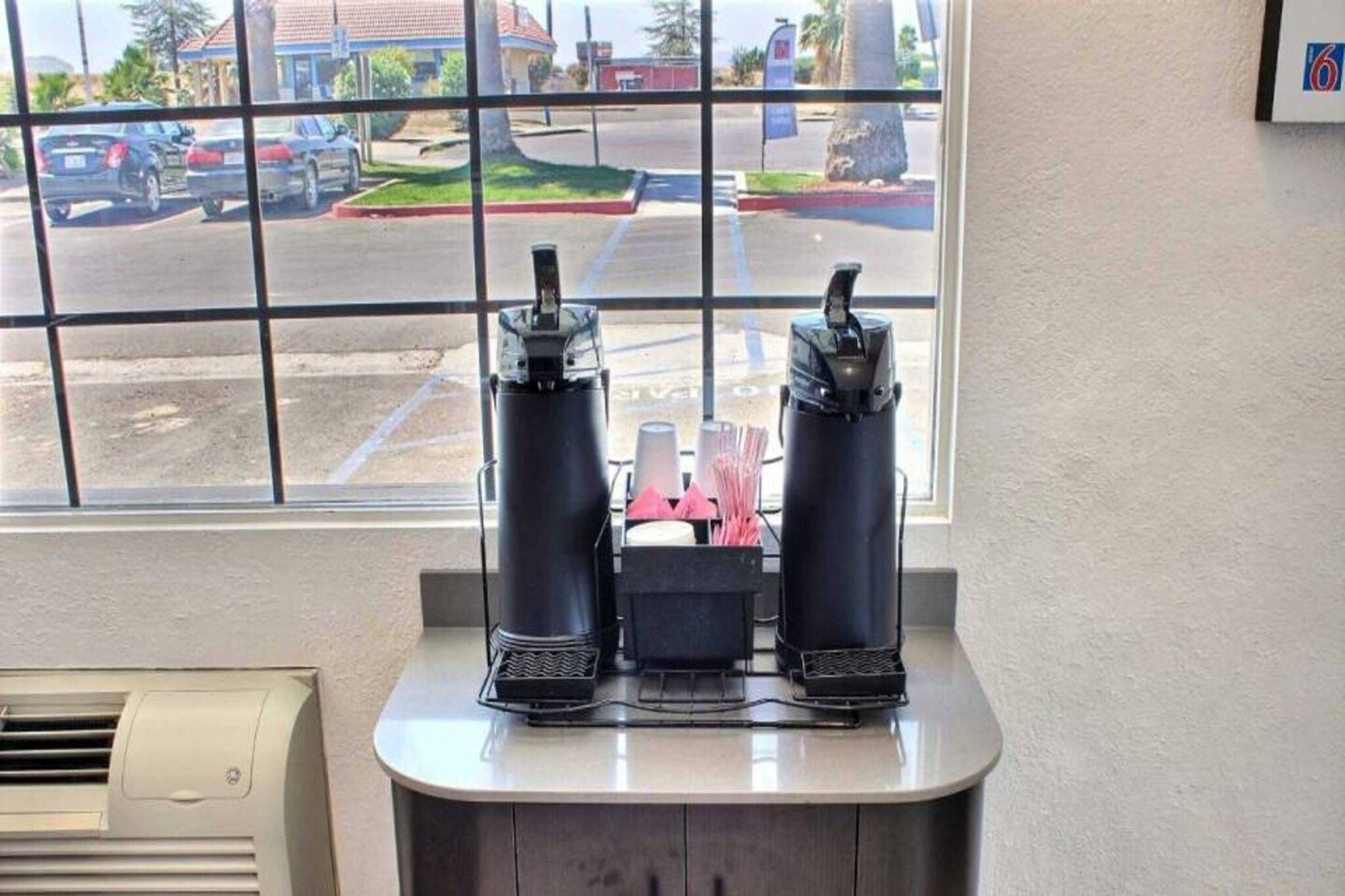 A window with a view of a parking lot and buildings outside.
