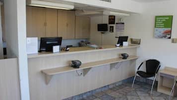 A reception desk with a computer, a telephone, and a small seating area with a chair.