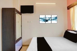 Una habitación de hotel con una cama, un televisor de pantalla plana montado en la pared y un conjunto de obras de arte abstracto sobre la cama.