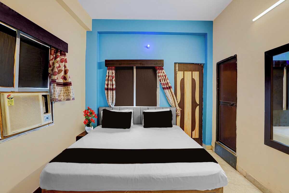Una habitación de hotel con una cama, cortinas, un ventanal y un aire acondicionado de pared.