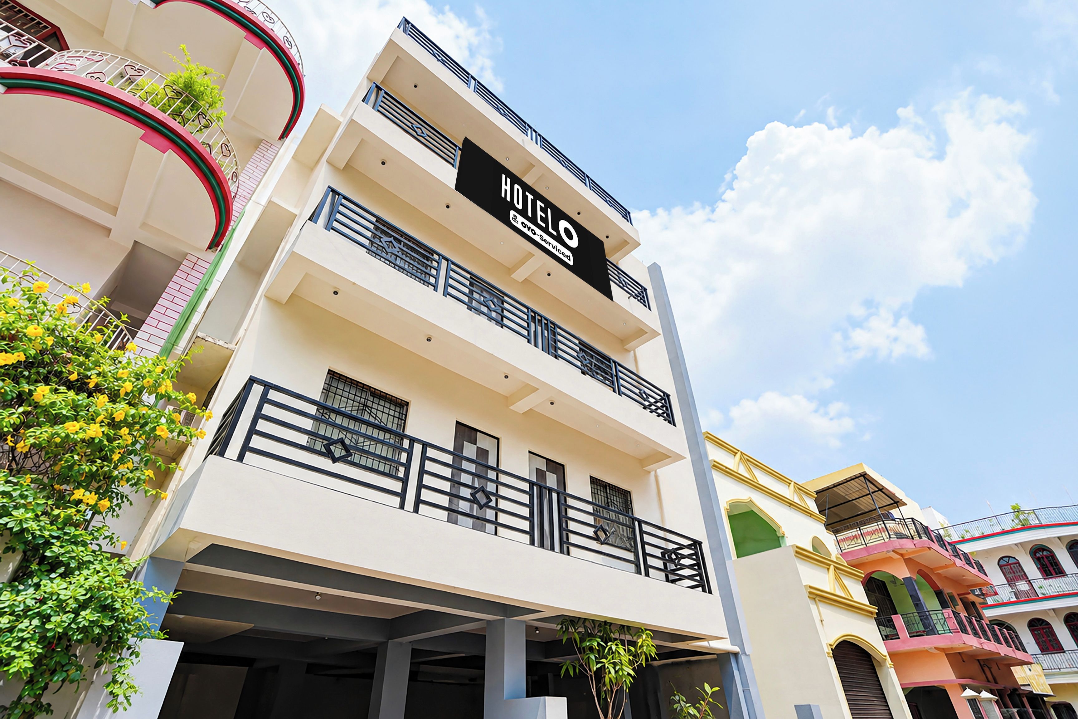 Un hotel de varios pisos con balcones, un cartel que indica que ofrece servicio y un cielo despejado.