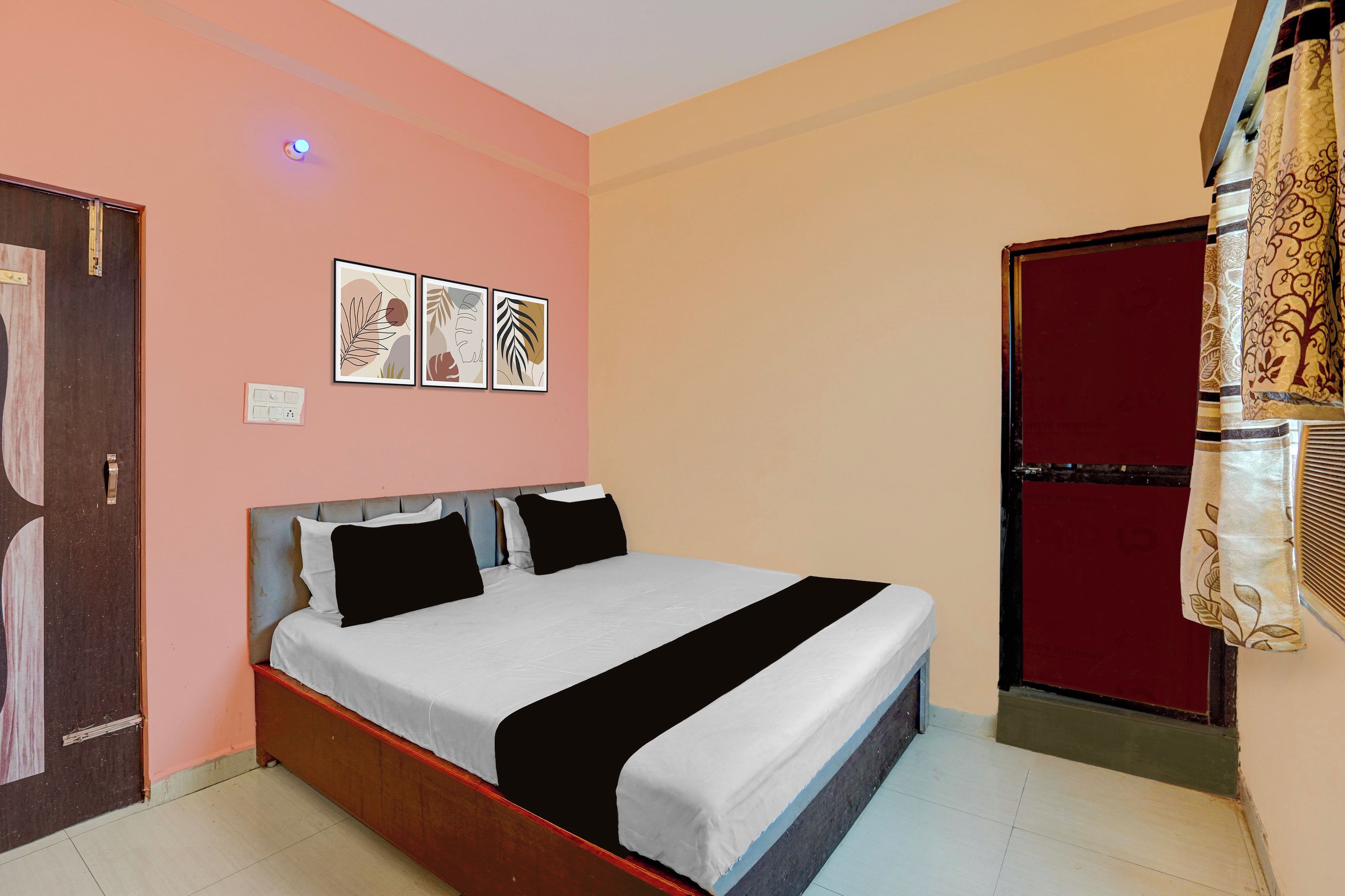 Un dormitorio con una cama, una puerta y una pared decorada con tres cuadros.