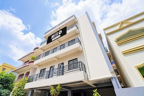 Un hotel de varios pisos con balcones, un letrero llamativo y un cielo despejado.
