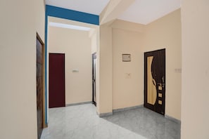 Un pasillo con suelo de baldosas, una puerta de diseño único y un enchufe de pared.