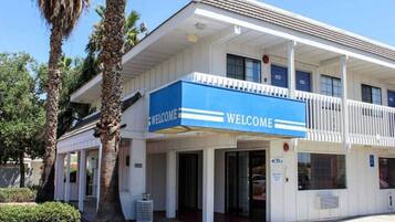 A building with a 'WELCOME' sign, multiple doors, and a parking sign.