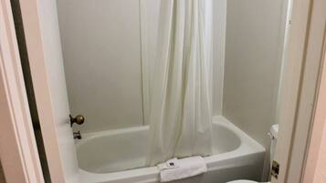 Een badkamer met een bad, toilet en een douchegordijn.