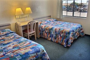 Ein Hotelzimmer mit zwei Betten, einem Schreibtisch, einem Stuhl und einem Fenster mit Blick ins Freie.