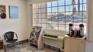 Una habitación con ventana, una silla, un tablón de anuncios, un calentador y una cafetera.