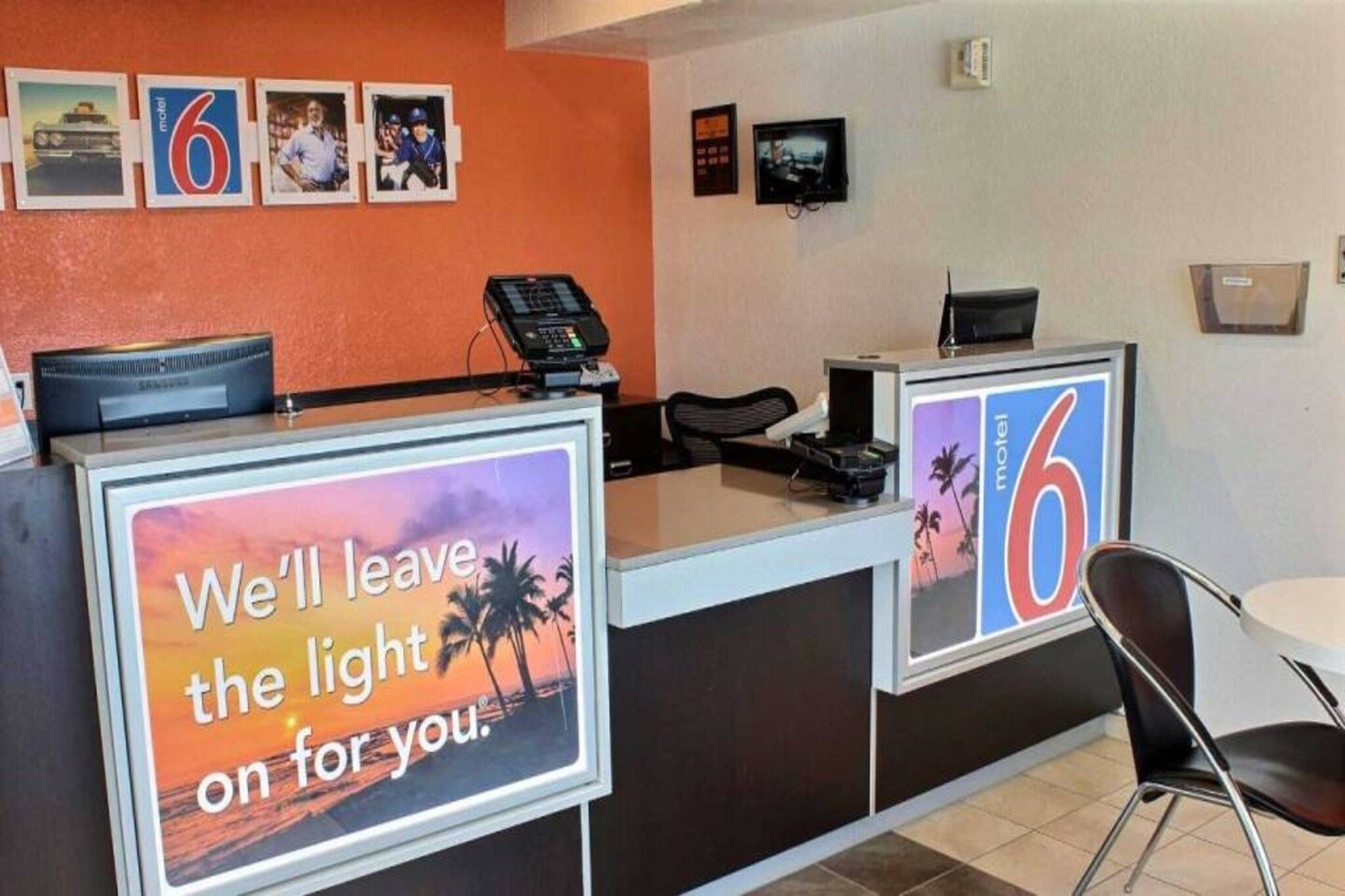 A motel reception desk with a sign that reads 'We'll leave the light on for you.'