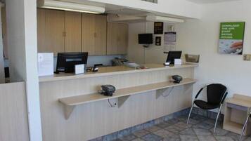 A reception desk with a computer, a telephone, and a small seating area with a chair.