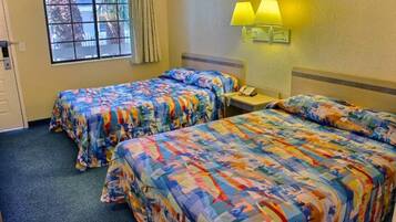A hotel room with two beds, a window, a lamp, and a telephone.