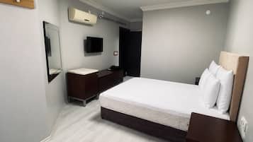 Une chambre moderne équipée d’un lit, de tables de chevet, d’un miroir, d’un téléviseur et d’un appareil de climatisation.
