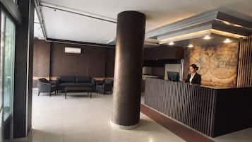 Un espace d’accueil moderne, doté d’une grande colonne, de sièges et d’un comptoir de réception.