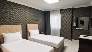 Une chambre d’hôtel avec deux lits, un bureau, un miroir et un luminaire au plafond.