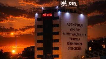 Un hôtel avec une enseigne bien visible portant l’inscription « DIÂ OTEL » et une grande enseigne lumineuse affichant un texte dans une langue étrangère.