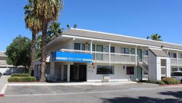 A two-story motel with a 'WELCOME' sign, a covered front porch, and a parking lot.