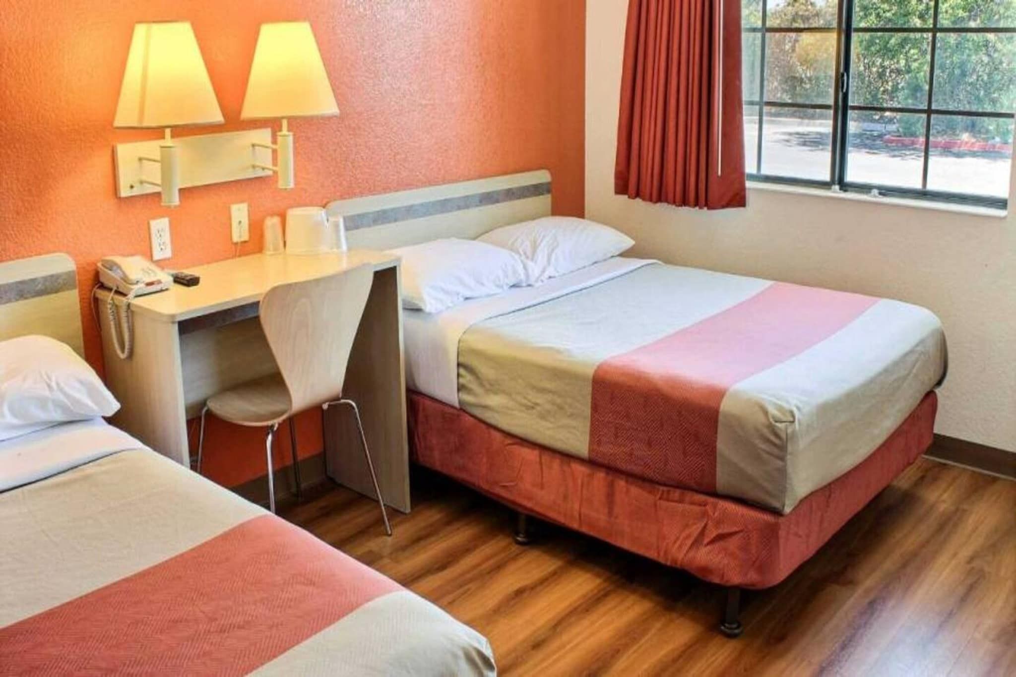 A hotel room with two beds, a desk, and a chair.