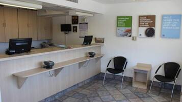 A reception area with a counter, computers, chairs, and informational posters on the wall.
