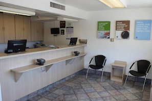 A reception area with a counter, computers, chairs, and informational posters on the wall. - 2 Queen Beds | Mini Fridge (Coalinga CA)