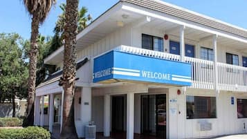 A building with a 'WELCOME' sign, a covered entrance, and a sign indicating an office.