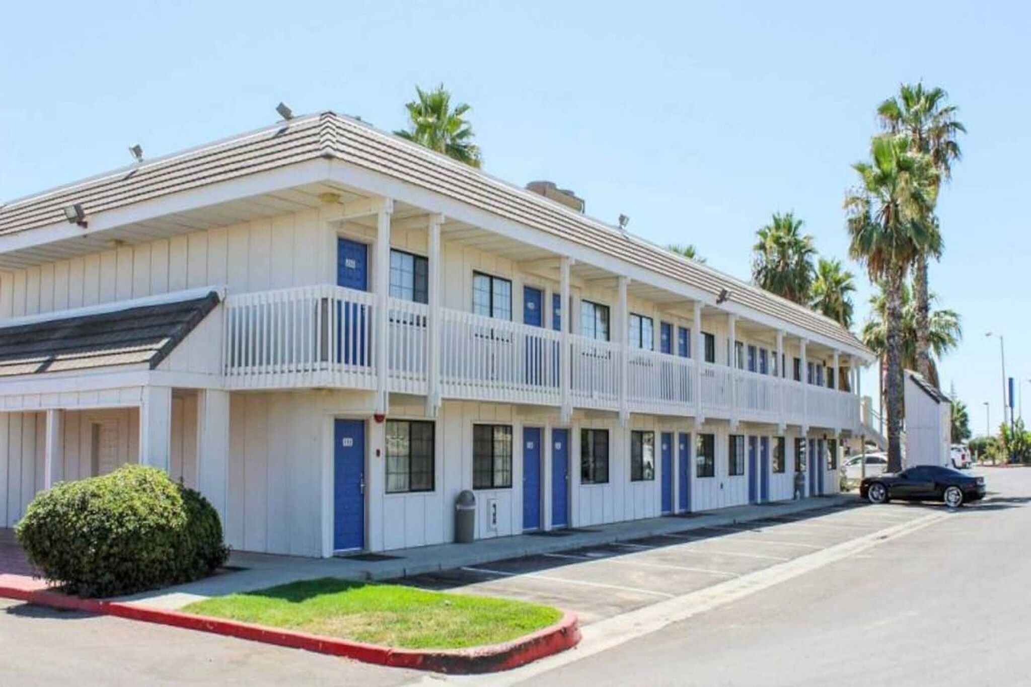 A motel with a two-story structure, multiple rooms, and a parking area.