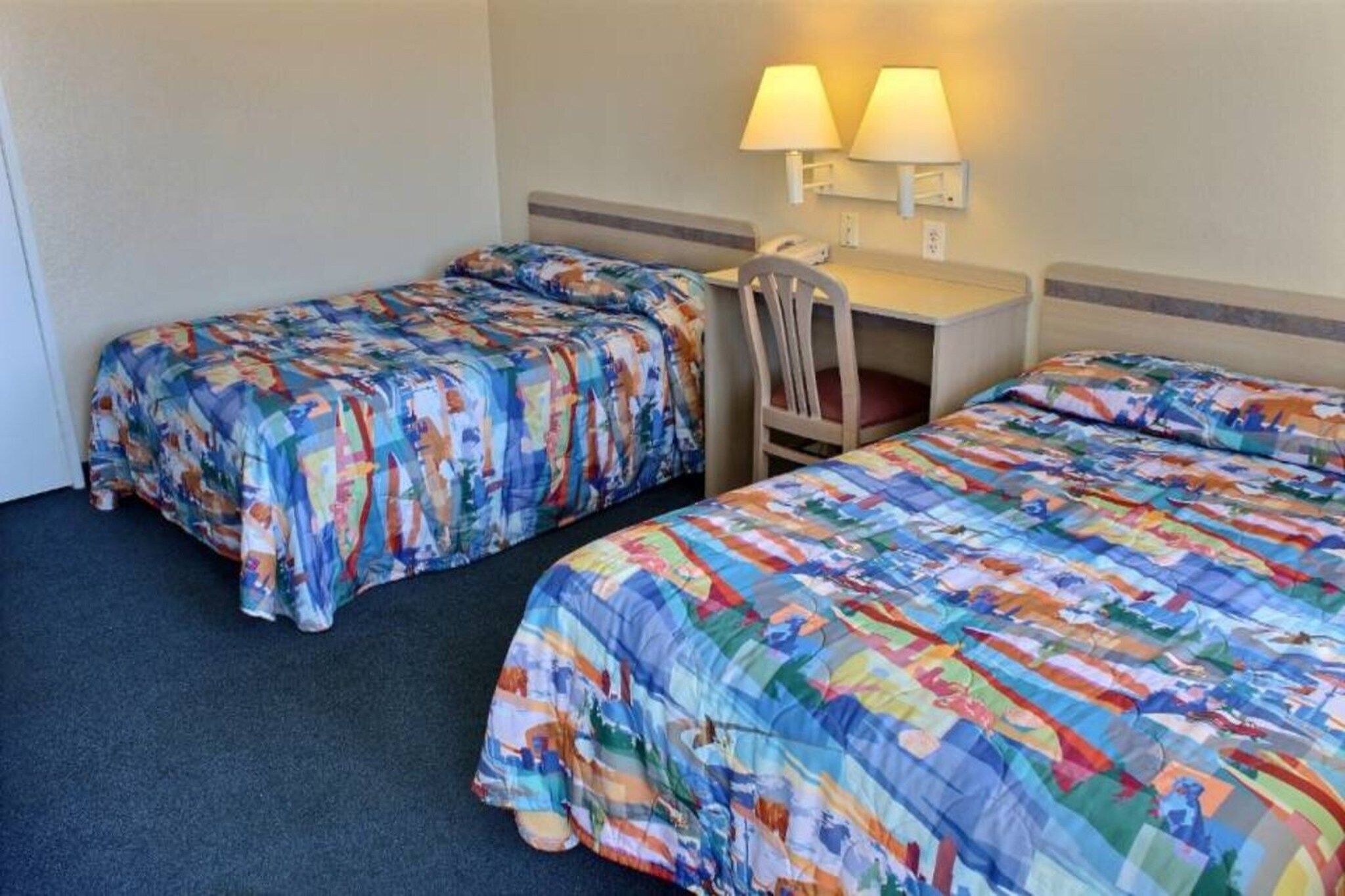 Een hotelkamer met twee bedden, een bureau en twee wandlampen.