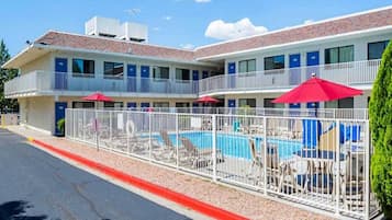A motel with a swimming pool, multiple balconies, and outdoor seating areas.
