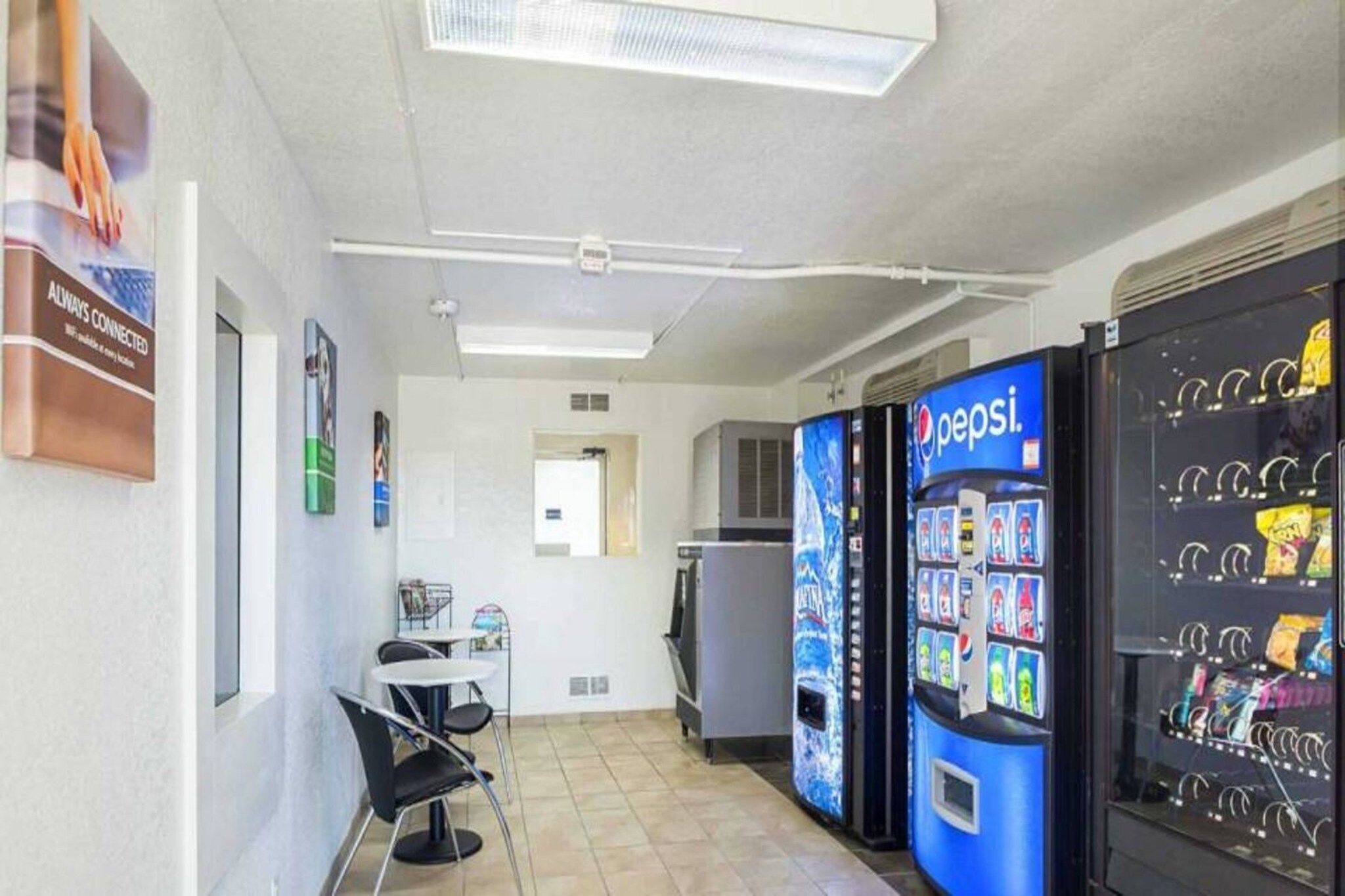 Un pasillo con máquinas expendedoras, un área de descanso y una puerta que da a otra habitación.