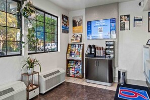 A room with a window, a plant, a wall-mounted shelf with books, a refrigerator, and a trash can. - San Luis Obispo 2 Queen Beds | Micfridge (San Luis Obispo)