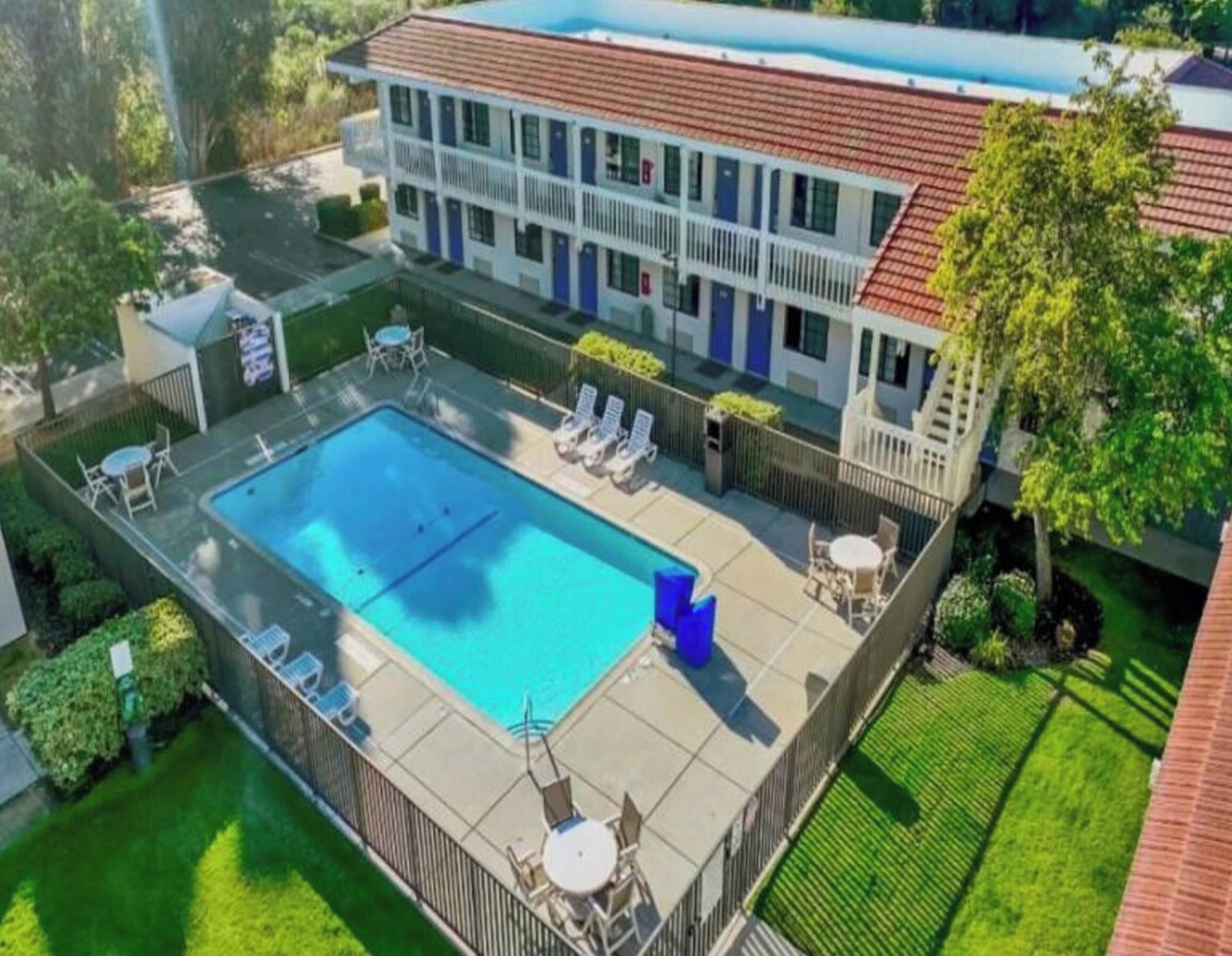A hotel with a swimming pool, outdoor seating, and a fenced patio area.