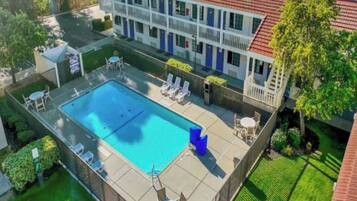 A hotel with a swimming pool, outdoor seating, and a fenced patio area.