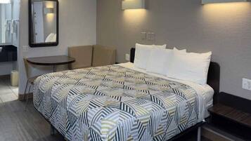 Ein Hotelzimmer mit einem Bett, einem kleinen Tisch, einem Stuhl und einem Spiegel.